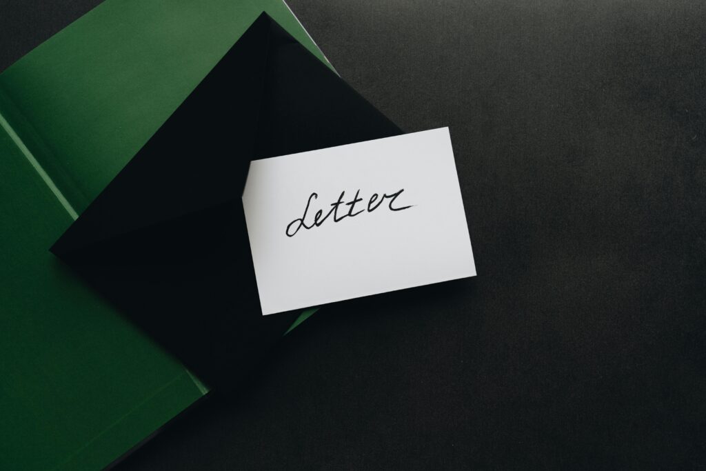 A flatlay showcasing a black envelope with a calligraphy letter, offering ample copyspace on a dark background.